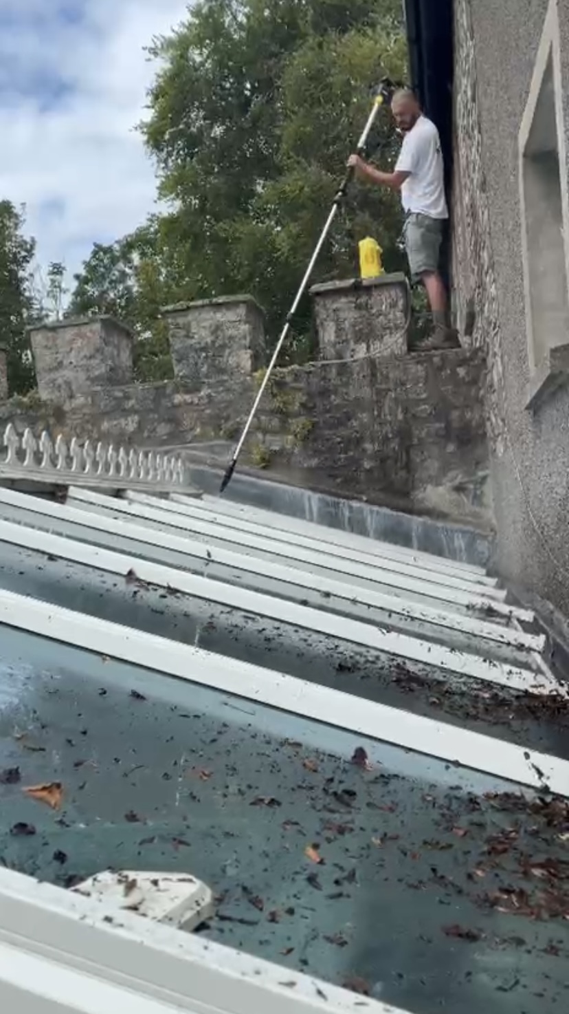 Cleaner using a water-fed pole to wash a conservatory roof