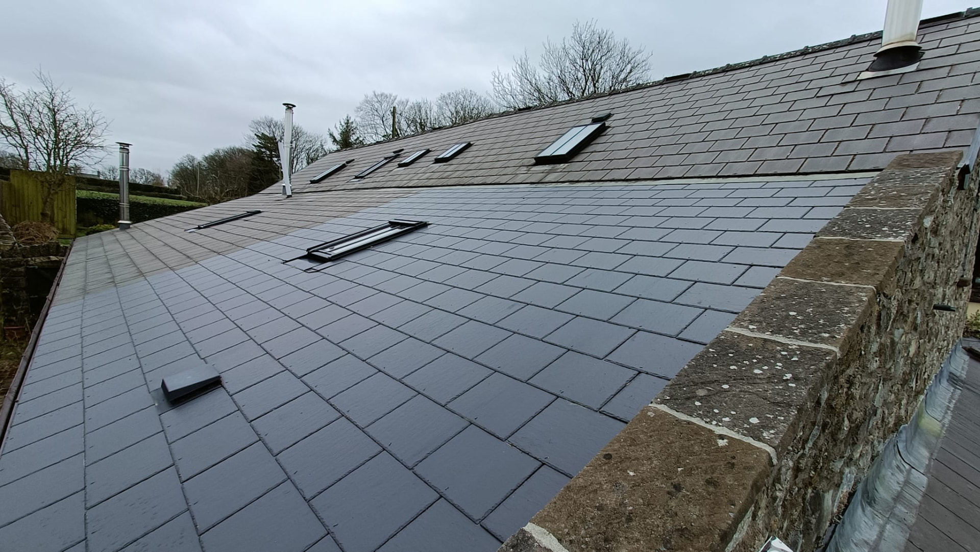 After: the same slate roof cleaned back to a clean, dark finish